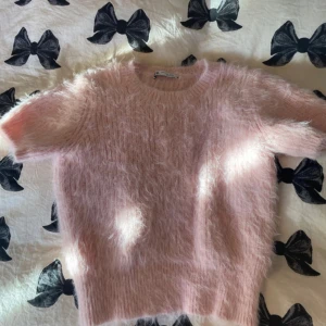 Fluffig rosa stickad tröja från Zara - Supermjuk och fluffig rosa stickad T-shirt från Zara med korta ärmar och rund hals. Tröjan har en tight känsla och är perfekt för dig som vill ha en mysig men ändå trendig look. Passar perfekt till jeans eller kjol för en söt vibe. 💞storlek M men väldigt liten i storleken så kommer skriva in XS som storlek😊