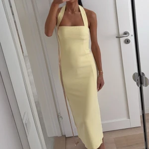 Ljusgul halterneck klänning 💛 - Ljusgul klänning med halterneck. Klänningen har slits bak och dragkedja i ryggen. Meshki Amelita dress 💛Använd en gång. 