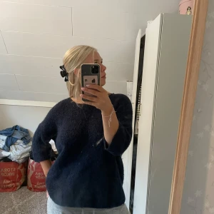 Mörkblå stickad tröja med trekvartsärm - Mysig mörkblå stickad tröja med trekvartsärmar och rund hals. Tröjan har en loose passform och är perfekt för kyligare dagar. Enkel och stilren design som är lätt att matcha med olika outfits.