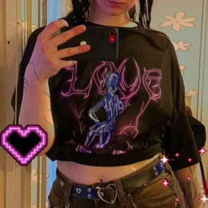 Svart t-shirt • futuristiskt neon tryck - Svart t-shirt i oversized passform. Framsidan har ett stort futuristiskt tryck med en robotbrud, lila blixtar och texten 'LOVE' i neonrosa. Materialet känns som bomull och t-shirten har en edgy vibe. 