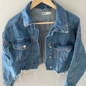 Blå croppad jeansjacka - Säljer en snygg blå croppad jeansjacka Gina tricot.  Perfekt till våren!