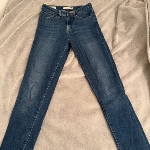 Blå jeans från Levi's - Snygga blå Levi's jeans i högmidjad skinny fit. De har en klassisk femficksdesign och fransade benslut för en trendig look. Perfekta för att ge din outfit en stilren touch. Passar till alla tillfällen! Nypris 999kr säljer för 70kr använd max 5 gånger