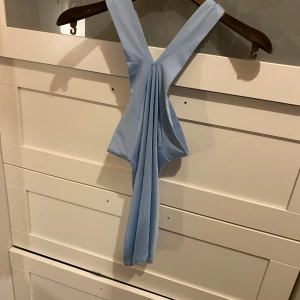 Ljusblå oneshoulder topp - Snygg ljusblå oneshoulder topp med en unik design där axelbandet korsar över axeln. Perfekt för en stilren och modern look. Materialet ser mjukt och bekvämt ut.