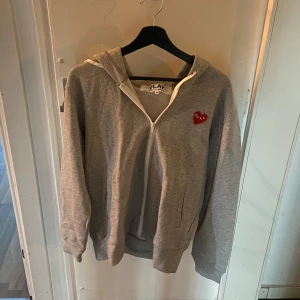 Grå hoodie från Comme des Garçons - Hej, jag säljer en stilren grå hoodie från Comme des Garçons. Hoodien är i storlek M och i toppskick då den inte har nå defekter eller fläckar. Dessutom är den väldigt bekväm och självfallet äkta. Pris kan diskuteras, buda gärna! 
