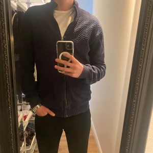 Mörkblå fullzip från Lindbergh - Säljer en stilig mörkblå fullzip från Lindbergh som knappast är använd. Storlek S och jag är 183 så sitter mer som M/L. Hör av er vid intresse