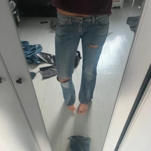 Lågmidjade Blå jeans med hål - lågmidjade Snygga blå jeans med hål. Storlek xs 34. De är lite mörkare i verkligheten. Midjemått ca 80cm. Innebenslängd 75cm. Rakt över är ca 38cm.