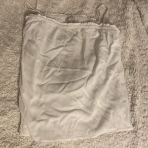 Vit ärmlös topp - Säljer en vit ärmlös topp med smala axelband. Toppen har en enkel och stilren design, perfekt för varma dagar. Materialet är lätt och luftigt, vilket gör den bekväm att bära.