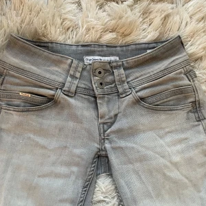 Grå jeans från Pepe Jeans - Säljer dessa så fina ljusgråa jeans från Pepe Jeans med dubbelknapp o snygga detaljer på fickorna. Org pris: 800 kr Jeansen är perfekt lågmidjade och bootcut. De är straight, men går ut lite nertill så är nästan flared. Jeansen är uppklippta längst ner för att få de att bli längre, därav det billiga priset. Det syns dock knappt när jeansen är på. Det är bara att skriva vid fler frågor elr bilder❤️