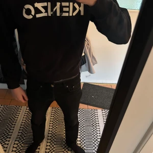  Kenzo tröja - Säljer en svart hoodie från Kenzo med vit logga på bröstet. Tröjan har en klassisk känguruficka och justerbar huva med snören. Perfekt för en stilren och bekväm look.