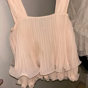 Ljusrosa blus från ASOS - Det är inte en fläck de är en skugga på tröjan ❤️Säljer en söt ljusrosa klänning från ASOS med volangdetaljer och plisserad design. Klänningen har en luftig passform och är ärmlös, perfekt för sommarens festligheter.