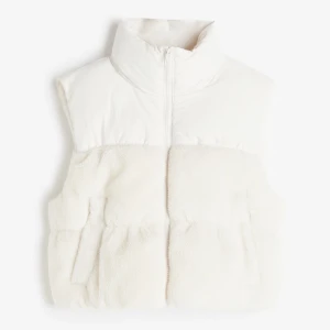 Vit pälsväst med dragkedja - Snygg och mysig vit pälsväst med dragkedja. Perfekt för att hålla sig varm och stilren under kyliga dagar. Västen har en hög krage och praktiska fickor.