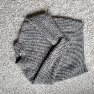 Grå stickad tröja från Zara - Säljer en mysig grå stickad tröja från Zara. Tröjan har en ribbad design och långa ärmar, perfekt för kyliga dagar. Den är både stilren och bekväm, ett måste i garderoben!