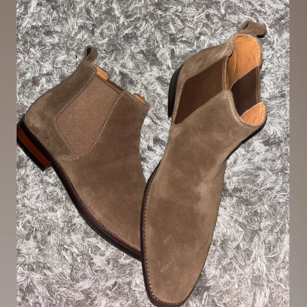 Dessa exklusiva Chelsea-boots är en riktig raritet – de tillverkas inte längre och är extremt svåråtkomliga. Designen efterliknar de ikoniska SLP-bootsen med sin eleganta silhuett, smala tå och stilrena finish i lyxigt mockaskinn. Dom är helt nya!. Kengät.