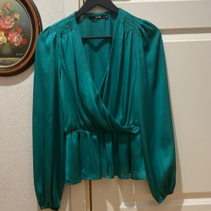 Very pretty -  "Elegant Teal Green Long-Sleeved Blouse with Charming White Polka Dots and Ruffled Hemline"?How about "Elegant Teal Green Long-Sleeved Blouse with Charming White Polka Dots and Ruffled Hemline"