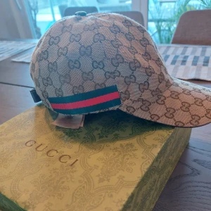 Gucci keps - Snygg beige keps från Gucci med deras ikoniska mönster. Kepsen har en justerbar rem baktill. Väldigt gott skick!