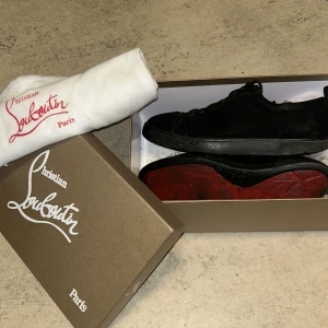 Svarta loubs - Säljer ett par svarta sneakers från Christian Louboutin med klassisk röd sula. Skorna har snörning och rund tå. Kommer med originalkartong och dustbag. De är i ganska dåliga skick,( högra skon)  hål högra skon 