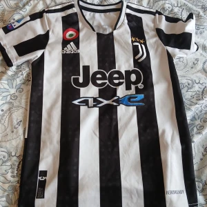 Juventus fotbollströja Dybala 10 - Juventus matchtröja med svartvita ränder, Adidas-logga och Jeep-sponsor på bröstet. Dybala och nummer 10 på ryggen. Klassisk design med klubbmärke och tre stjärnor. Kortärmad modell i lätt material.