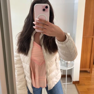 Beige lätt dunjacka - Säljer en beige pufferjacka med dragkedja framtill. Jackan har en quiltad design och är lätt vadderad, perfekt för kyligare dagar. Modellen är normal i passformen och har långa ärmar. Enkel och stilren look som passar till jeans.