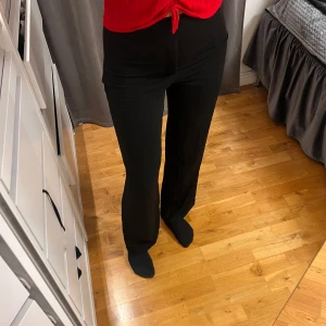 Svarta vida kostymbyxor - Säljer ett par svarta kostymbyxor med hög midja och raka, vida ben. Byxorna har en klassisk look och är perfekta för en stilren outfit. De är tillverkade i ett mjukt material som ger en snygg passform och är riktigt bekväma. Från Bikbok, storlek Xs i modellen PW ADRIANA.