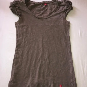 Brun kortärmad topp från edc - Säljer en brun kortärmad topp från edc med rund halsringning och rynkade detaljer vid axlarna. 