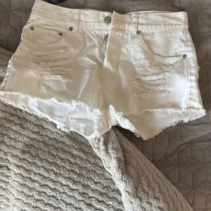 Vita lågmidjade jeansshorts med slitningar från Bik Bok - Säljer ett par vita jeansshorts från Bik Bok i storlek XS. Shortsen har slitna detaljer framtill, fransig kant nertill och klassisk femficksmodell. Perfekta för varma dagar och har en snygg, avslappnad look.skriv gärna❤️🥰🥰