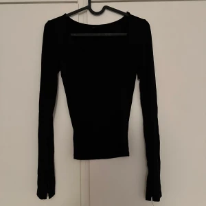 Svart långärmad topp med rund hals - En stilren svart långärmad topp med rundad halsringning. Perfekt att matcha med jeans eller kjol för en enkel och snygg look. Tunn och stretchig i materialet.
