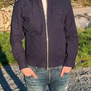 Mörkblå overshirt med dragkedja  - Säljer en stilren mörkblå overshirt med diskreta vita prickar. Jackan har två bröstfickor med lock och hel dragkedja framtill. Perfekt för lager-på-lager och enkel att matcha till jeans. Pris kan diskuteras! (Skriv vid minsta fundering) snabb affär= att ni kan få för 400kr