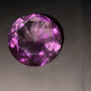 Stor rosa diamantformad prydnadssten - Säljer en stor, glittrande diamantformad prydnadssten i rosa färg. Perfekt som dekoration eller accessoar till rummet. Stenen har många fasetter som reflekterar ljuset snyggt och ger en lyxig känsla.