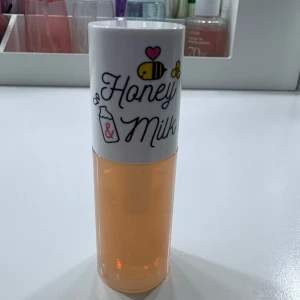 Honey & Milk läppolja - Söt läppolja med motiv av bi och mjölk på locket. Oljan är ljusgul och kommer i en genomskinlig tub med vitt lock. Perfekt för att ge läpparna glans och fukt. Innehåller troligen honung och mjölkextrakt. Testat på handen