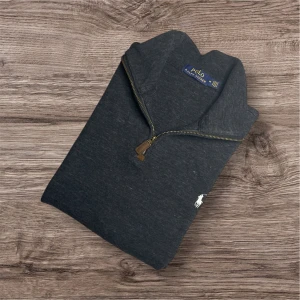 Ralph Lauren Half-Zip – Mörkgrå (M) - Ralph Lauren Half-Zip – Mörkgrå (M) Säljer en stilren och klassisk Ralph Lauren half-zip i mörkgrått 🖤. Bekväm tröja i mjukt material med kabelstickat mönster och broderad logga på bröstet 🐎 	•	Färg: Mörkgrå ⚫ 	•	Storlek: M 	•	Mått: 📏 Längd 65 cm, armhåla till armhåla 60 cm, axel till axel 50 cm 	•	Perfekt skick ✅ 	•	Nypris: 3000+ kr 💸 	•	Snittpris på Vinted: ca 1200 kr 📊 107 Passar perfekt för höst, vinter eller sena sommarkvällar! 