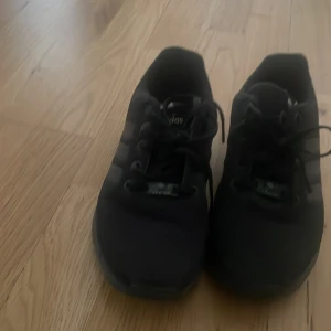 Svarta Adidas Torsion sneakers - Säljer ett par svarta Adidas Torsion sneakers med klassisk snörning och diskret design. Skorna har rund tå och platt sula, perfekta för en sportig och stilren look. Adidas-loggan syns tydligt på plösen.