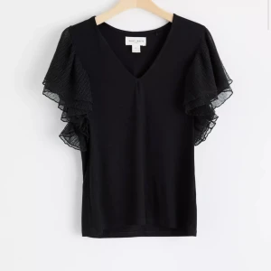 Svart topp med volangärmar - Svart topp med v-ringning och mesh volangärmar. Väldigt bra skick, inga defekter och är stretchig i materialet. Mjukt material och luftig känsla. Sista bilden är lånad 🌸