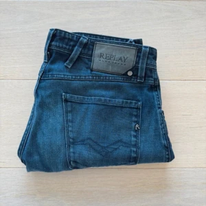 Replay Anbass jeans herr W32 - Säljer ett par blå Replay Anbass jeans i herrstorlek W32. Klassisk femficksmodell med normal passform och raka ben. Jeansen har snygga slitningar och Replay-logga på bakfickan. Perfekta för dig som gillar stilrena och bekväma jeans.