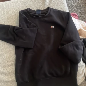 Svart sweatshirt från Champion - Svart sweatshirt från Champion med klassisk logga broderad på bröstet. Tröjan har rund halsringning och långa ärmar. Perfekt för en avslappnad och sportig stil.💕