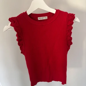 Röd ribbad linnetopp med volang från Stradivarius - Säljer en röd ribbad linnetopp från Stradivarius med volangdetaljer längs ärmhålen. Toppen är ärmlös och har en rund halsringning. Passar på mig som har storlek XS/S😊