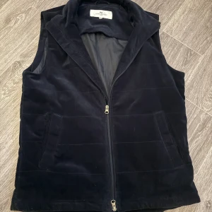 Navy blå manchester väst från John Henric - Den SÄLJS INTE LÄNGRE!! Ny pris 1900 mitt pris 1,099. Helt ny.                               Navy blå  svart manchester väst från John Henric med dragkedja framtill. Perfekt för att lägga till en stilren touch till din outfit. Väst i storlek M.