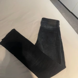 Mörkblå/svarta Jack and Jones jeans - Snygga mörkblå/svarta slim fit jeans från Jack and Jones i storlek 29/32. Använda 2 gånger och nypris på denna färg/modell ligger på ungefär 800, mitt pris endast 199! Hör av dig vid minsta fundering!