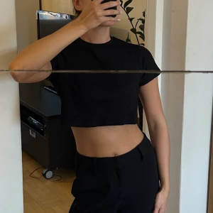 Svart croppad t-shirt - En enkel svart croppad t-shirt med rund halsringning och korta ärmar. Passar bra till vardag! Helt oanvänd 