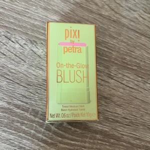 Pixi On-the-Glow Blush Fleur - Helt ny, Pixi On-the-Glow Blush i nyansen Fleur är en krämig blush-stick som ger en fräsch rosa ton till kinderna. Kommer i en smidig grön förpackning med guldiga detaljer och innehåller 19g. Perfekt för att snabbt få glow och färg på språng.