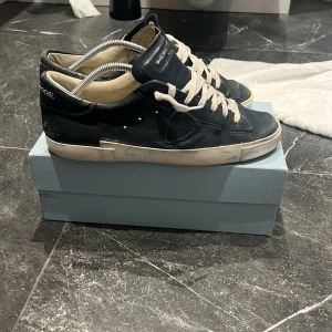 Philippe Model 44 - Mörk blå Philippe Model sneakers i skinn med vita snören och vit sula. Klassisk modell med inga defekter. Har använt skorna sparsamt och kommer med box. Skrive gärna om frågor eller mer bilder om skorn.
