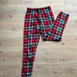 Rödrutiga pyjamasbyxor med snörning - Supermysiga pyjamasbyxor i röd, vit och grön rutig design. Byxorna har snörning i midjan och är gjorda i mjukt bomullstyg. 