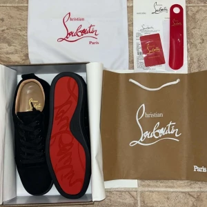 Christian Louboutin svarta sneakers mocka - Jag säljer ett par Svarta sneakers  Christian Louboutin i lyxig mocka med klassisk röd sula och diskret logga undertill. Skorna har rund tå, svarta skosnören och en stilren design som sticker ut med den ikoniska röda undersidan.