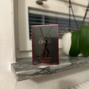 Yves Saint Laurent Black Opium 90ml - Black Opium från Yves Saint Laurent är en ikonisk parfym i en snygg svart och rosa kartong. Flaskan rymmer 90 ml och doften är känd för sina djupa, sensuella toner. Perfekt för dig som gillar lyxiga och moderna parfymer.