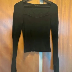 Svart ribbad långärmad tröja Gina Tricot - Svart långärmad tröja från Gina Tricot med ribbad struktur och snygg fyrkantig ringning. Tröjan är tight i modellen och har långa ärmar med tumhål, perfekt för en stilren och enkel look.