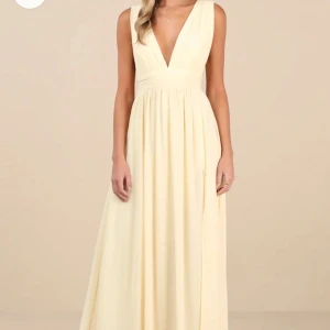 Ljusgul långklänning med djup v-ringning - Superfin långklänning i ljusgul ton med djup v-ringning både fram och bak. Klänningen har breda axelband, markerad midja och ett mjukt, fallande tyg som ger en elegant siluett. Perfekt för sommarens speciella tillfällen.