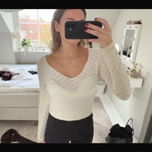Vit stickad långärmad topp - Supersöt vit stickad topp med lång ärm och v-ringad hals. Snyggt mönster i hela tyget och figurnära passform som framhäver siluetten. Perfekt att styla med jeans eller kjol för en fräsch look.