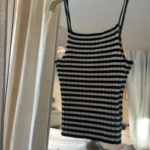Randig ribbad linnetopp svart/vit - Säljer en ribbad linnetopp med smala axelband i svart och vitt. Toppen har ett tight passform och är randig med horisontella ränder. 