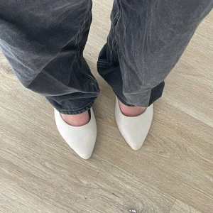 Beige ballerinaskor med låg klack - Stilrena ballerinaskor från dinsko i beige mockaliknande material. Skorna har spetsig tå och en låg klack med snygg strukturdetalj. Perfekta för dig som gillar en clean och modern look med en twist.