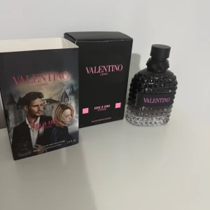 Valentino Uomo Born In Roma Intense 100ml - Parfymen Valentino Uomo Born In Roma Intense kommer i en snygg svart och transparent glasflaska med nitar och rosa detaljer. Förpackningen är svart med rosa text och rymmer 100 ml Eau de Parfum Intense. Flaskan har en lyxig och modern design.