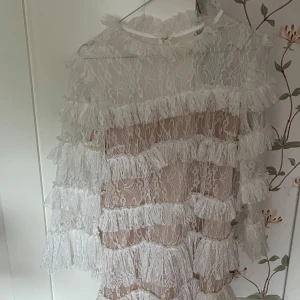 Vit spetsklänning med volanger - Superfin vit klänning i spets med flera lager volanger och transparenta detaljer. Klänningen har lång ärm och hög hals, perfekt för dig som vill sticka ut med en romantisk och trendig look. Det är en by Malin klänning  det är bara fråga om en bättre bild på klänningen 💕